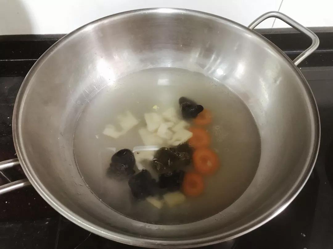 锅内倒水和高汤煮开，放入冬笋、胡萝卜、木耳煮至半熟。