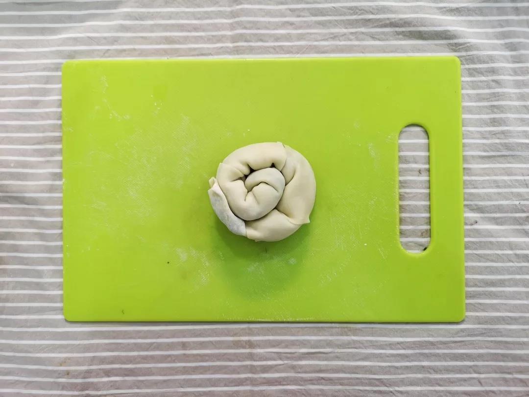 将卷好的馄饨皮从一头盘成螺旋的面团。