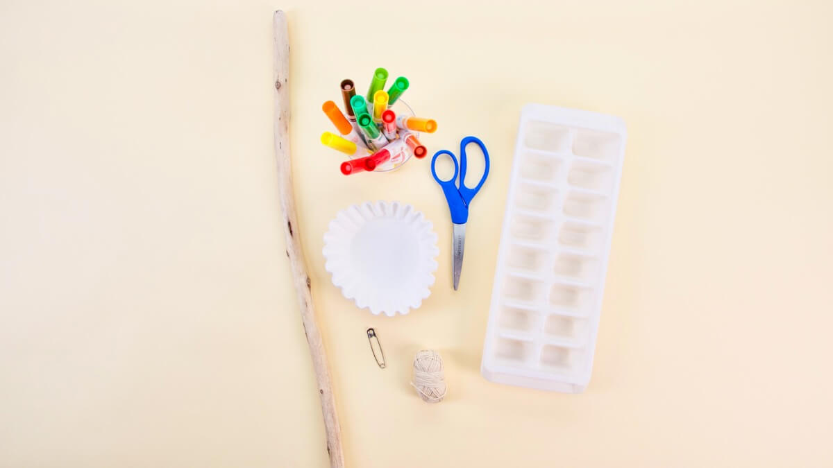 步骤1：材料准备：叶子(可选)、咖啡滤纸、可水洗记号笔、冰块托盘、彩笔、剪刀、线、胶带、曲别针、木棒、纸板表面让其干燥