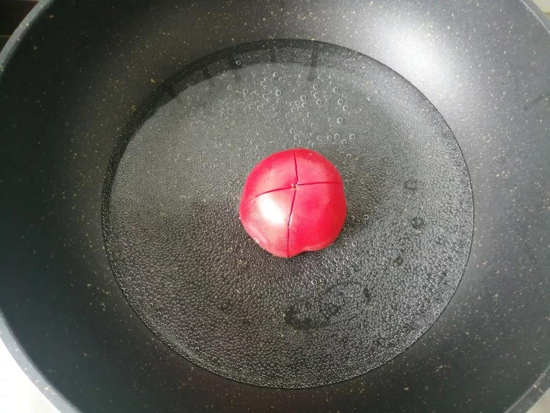 将番茄去蒂洗净，用刀在光滑面打十字刀，沸水中煮20秒。