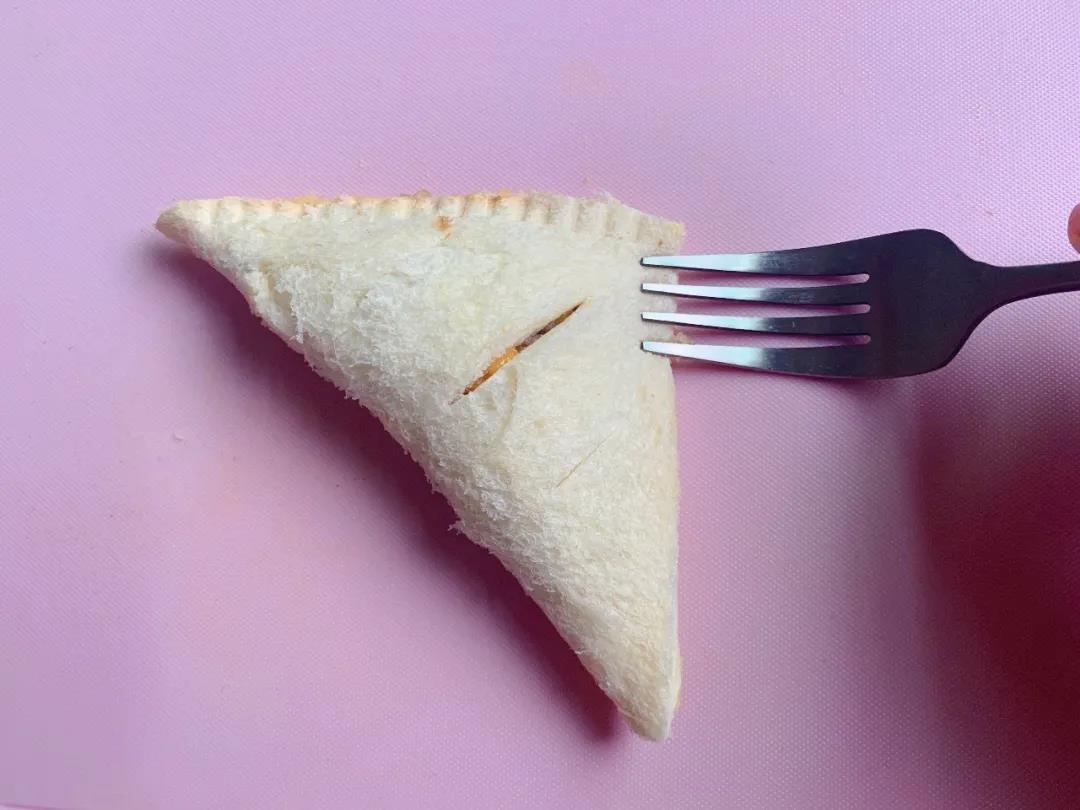 吐司另一边翻过来盖起来，呈三角状，用叉子沿着边压实。