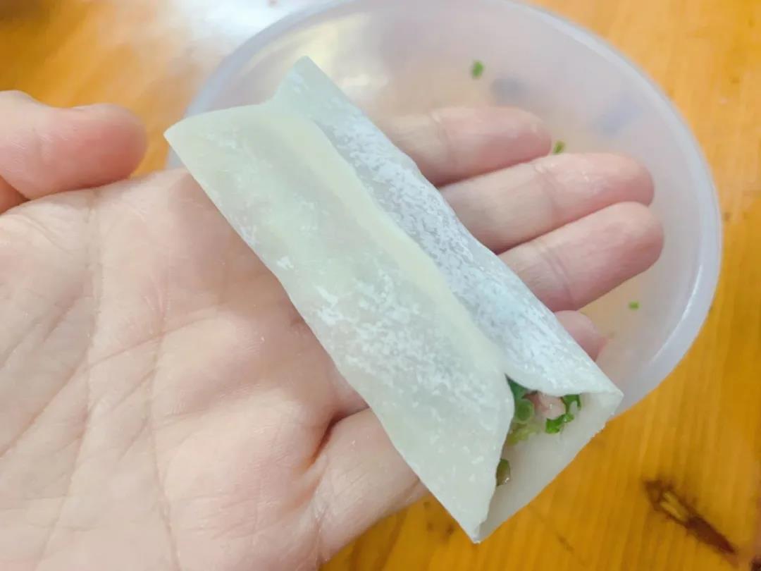 第7步：饺子皮两边提起对捏捏紧，两端不封口。