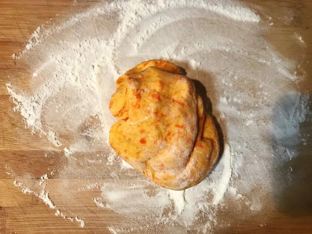 案板上撒少量干面粉，取出发酵好的面团，按压排气。