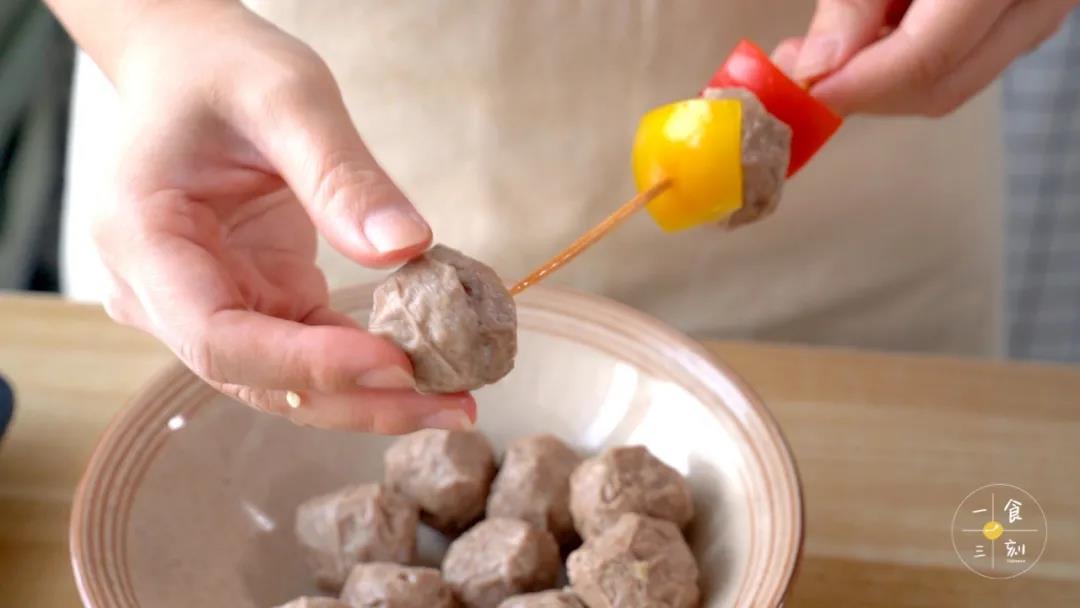 用竹签把牛肉丸和彩椒串成串串，放到烤盘上