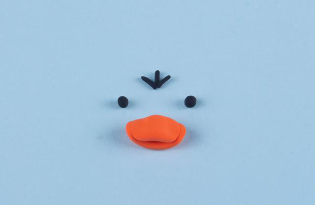 步骤2：然后用桔红色粘土做出小黄鸭的嘴巴，黑色粘土做出眼睛和头发。