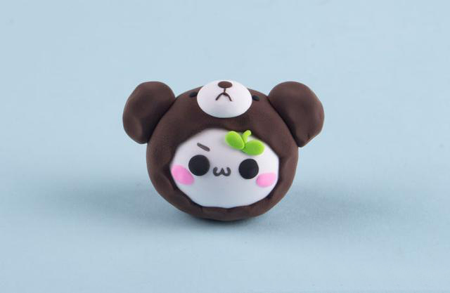 步骤5：把咖啡色半球壳包裹在团子的头上，然后粘上耳朵嘴巴和眼睛，小熊原型的帽子就做好了。然后把做好的小草芽粘到额头部位。