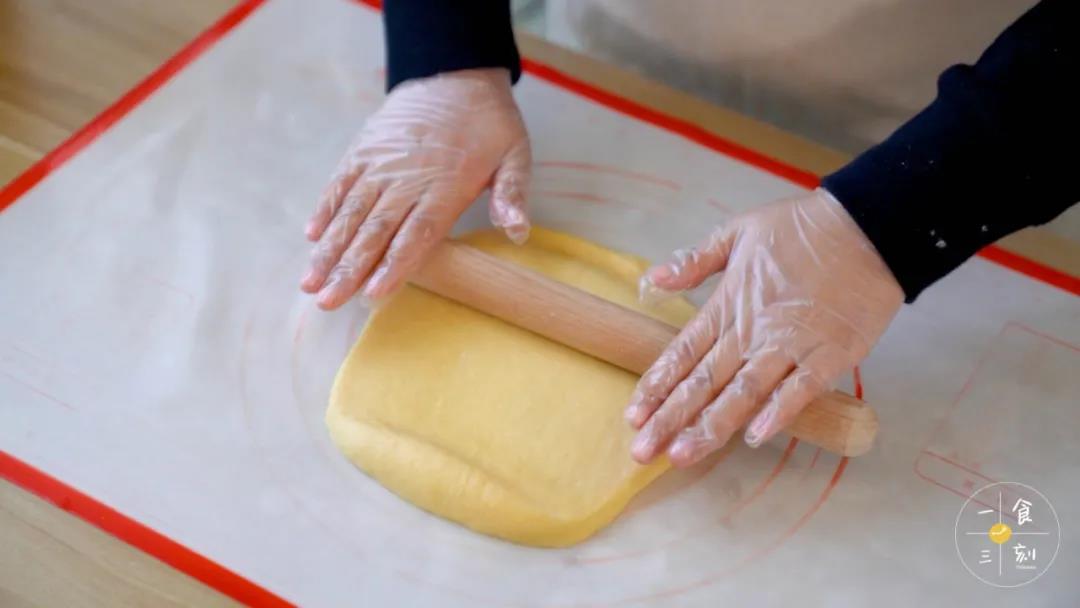 取出面团，擀成薄片，铺上椰蓉馅，卷起、整理封口后放入面包机