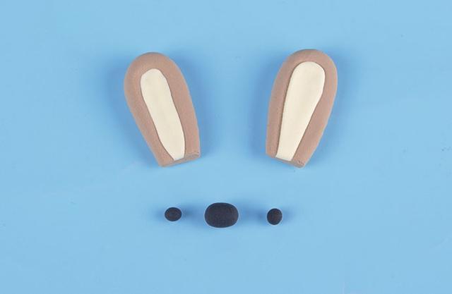 步骤2：用浅咖色粘土和浅黄色粘土做出小兔子的耳朵，黑色粘土揉三个小圆球，两个小的做眼睛，一个大的做鼻子。