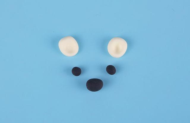 步骤4：接着我们用浅黄色粘土做出两只小耳朵，黑色粘土做出眼睛和鼻子。