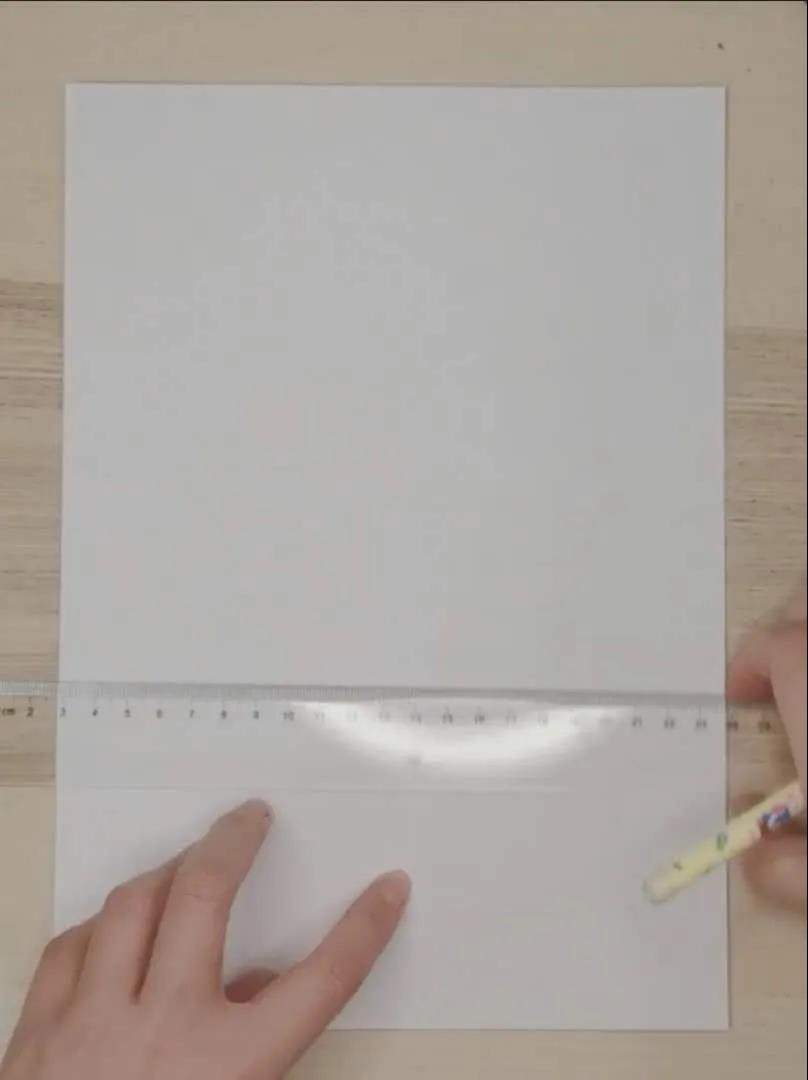 步骤1：竖着用纸，先在白纸上画出一条直线，直线在画纸的中间偏下方，上面留的空间大一些下面略小一些；画完后将纸左右对折，再打开进行下一步。