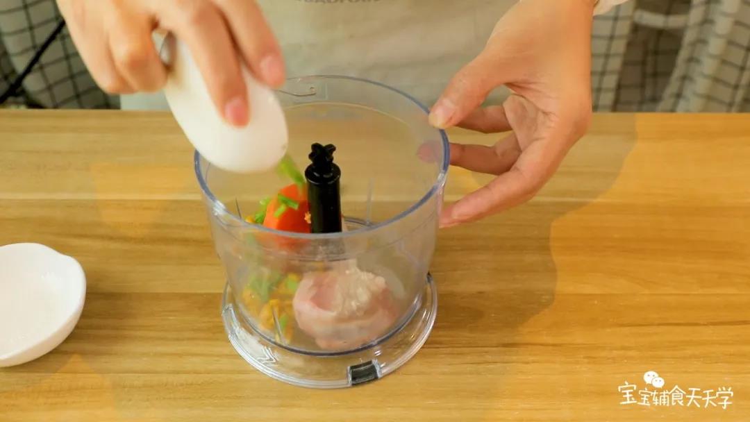 将猪肉、胡萝卜、玉米粒、蛋清和葱花，倒入搅拌机中搅拌均匀