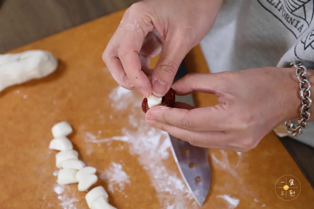 将糯米小团夹入红枣中，用手指捏合一下