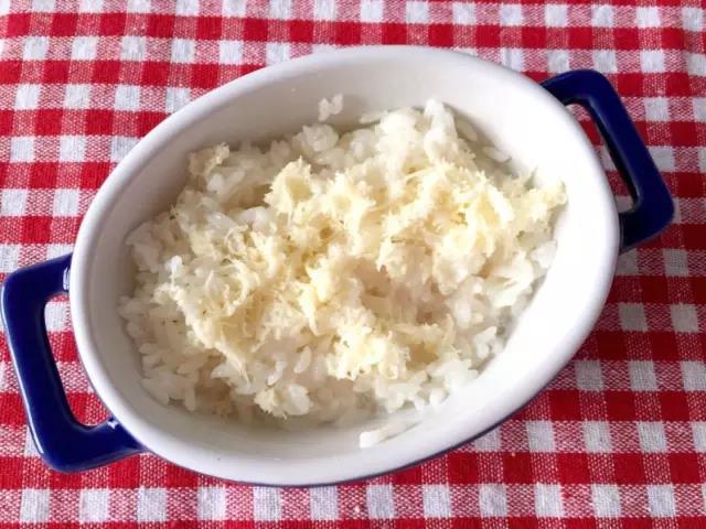 米饭和牛奶拌匀放在烤碗底部，铺上一层芝士。