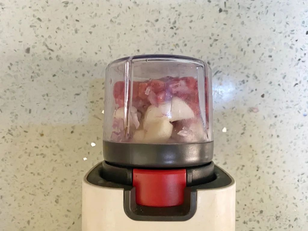 将牛肉、山药、洋葱碎加入到料理机杯中，搅打成黏稠的牛肉糊。