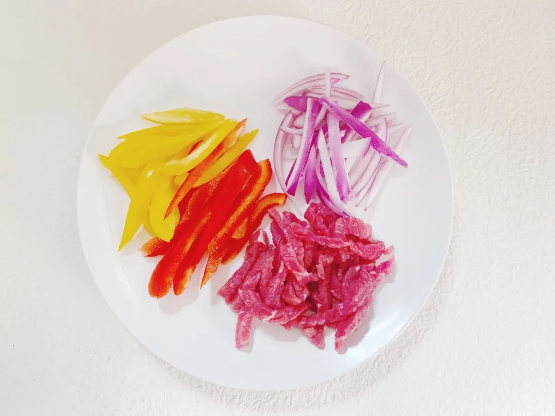 牛肉洗净擦干切细条，红椒、黄椒洗净去蒂去籽切条，洋葱洗净去皮切条。