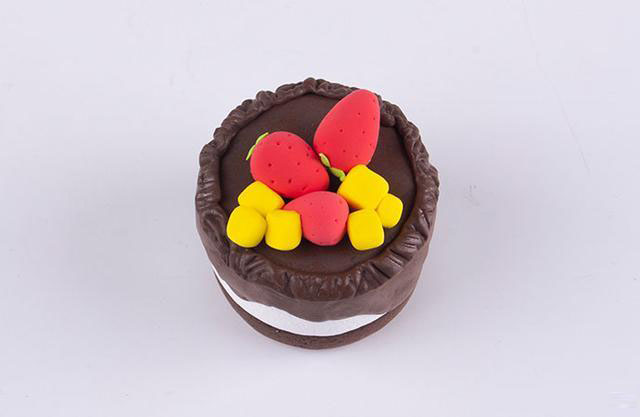 步骤7：蛋糕顶层周边围上一圈咖啡色的细条，然后用工具压出纹理，最后把草莓和芒果粒放在上面，如图所示。