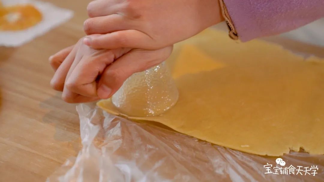 用模具将面片切成圆形，摆在烤盘上，铺上橙子片