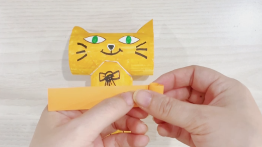 步骤8：选一个同色系的长条卡纸卷起来，贴在猫咪的尾部。