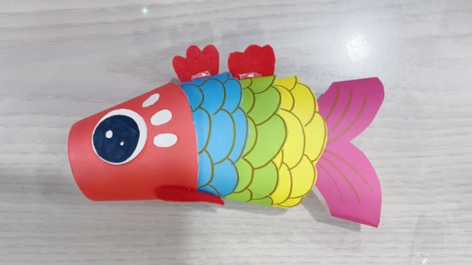 步骤7：用卡纸给鱼贴上眼睛、装饰和鱼鳍。