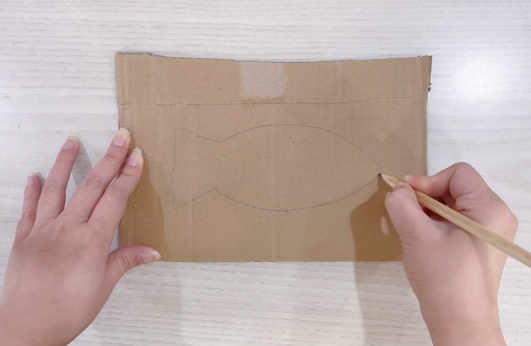 步骤1：在纸板上画出鱼的形状并剪下来。