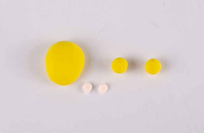 步骤3：用黄色粘土做出后脑勺。再做两个小圆球作为头上的小揪揪，肉色粘土做出两只耳朵。