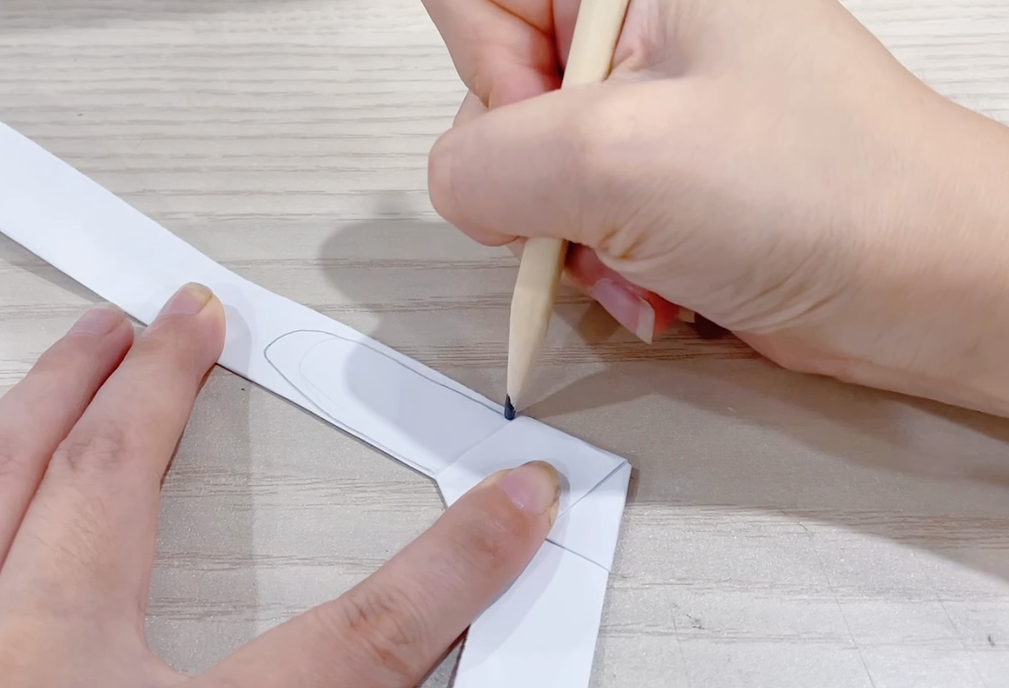 步骤3：一端画上兔子耳朵的轮廓并剪下。