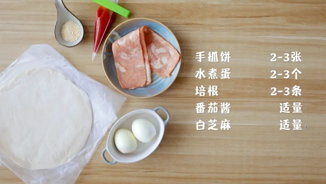 食材准备：手抓饼2-3张，水煮蛋2-3个，培根2-3条,番茄酱 适量，白芝麻适量