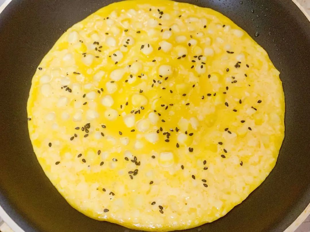 面糊半凝固时，撒上熟黑芝麻，继续煎至两面熟。