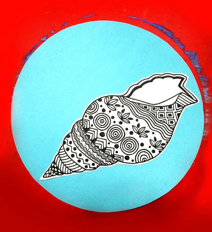 步骤3：接着我们把画好的“海螺”剪下，并粘贴到事先准备好的蓝色圆形卡纸上。