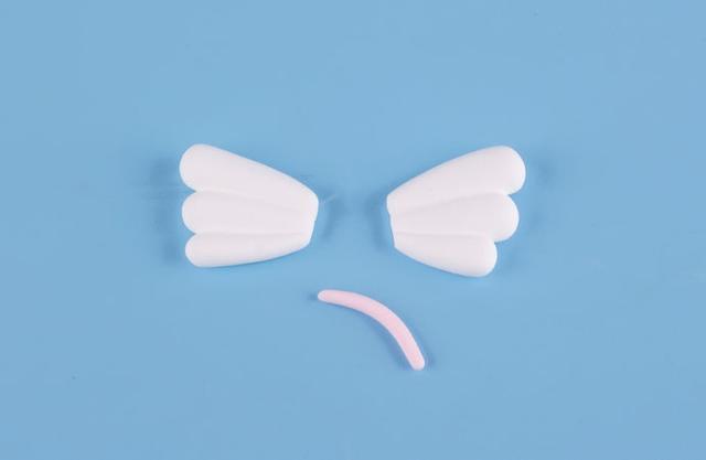 步骤8：因为是小飞象，我们需要给它做出能够飞翔的翅膀，按照上图的样子用白色粘土做出小翅膀，然后粉红色粘土揉一根小细条作为尾巴。