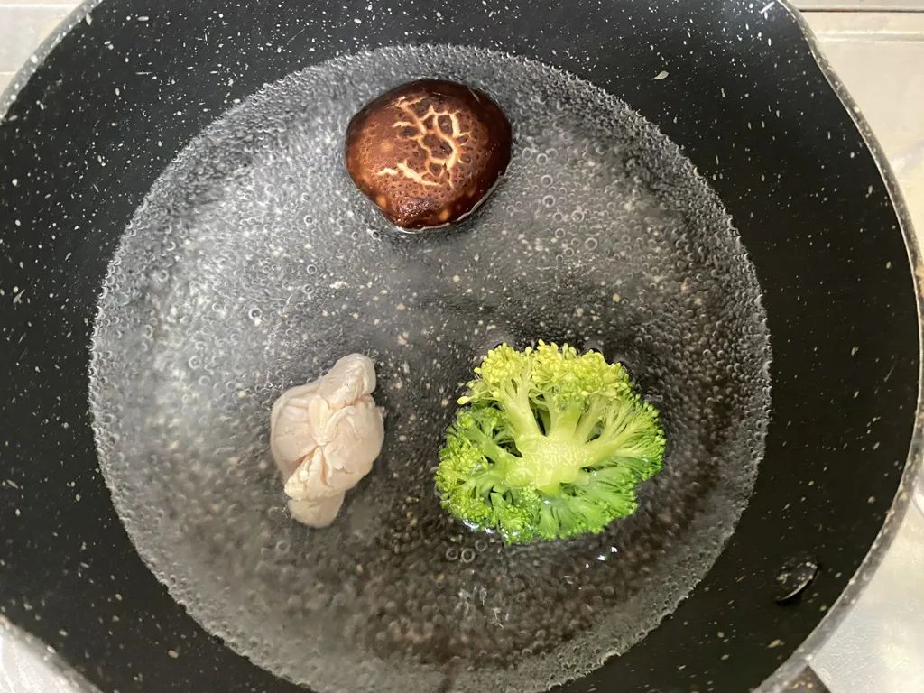 锅里放入洗净的香菇、西兰花、鸡肉煮至熟。