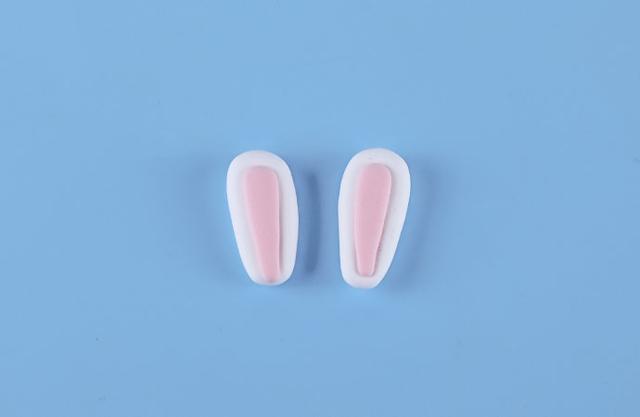 步骤8：用白色粘土做两个大的水滴形压扁，粉红粘土做小的水滴形粘在上面，做出小兔子的耳朵。