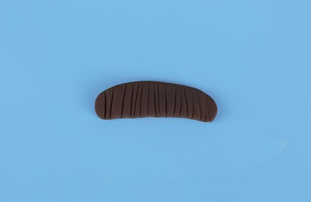 步骤4：然后用咖啡色粘土做一个圆柱形压扁，在上面压出纹路，如上图所示，这是小红帽的头发。