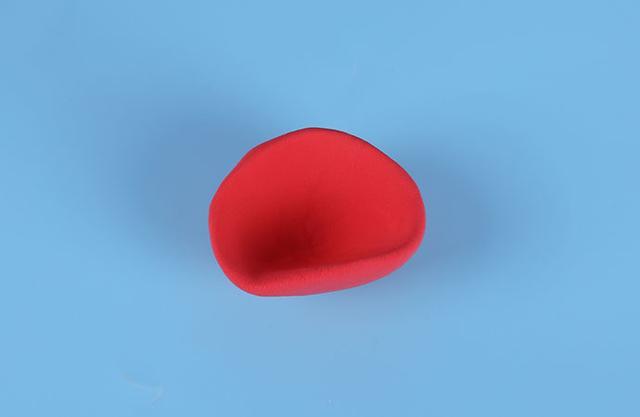 步骤6：用大红色粘土做一个圆形然后整理一下整成帽子的形状，如上图所示。