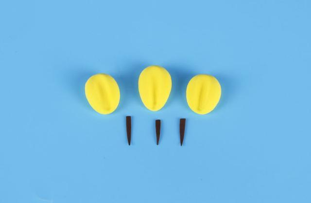 步骤4：黄色粘土揉成小水滴形状，然后用工具在中间压一下，如上图所示，这是向日葵花盘的小花瓣。再用咖啡色粘土做出三根细长的水滴形。