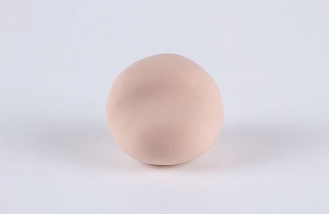 步骤1：我们在做小狗之前需要混一下颜色，用少量咖啡色粘土+一些肤色粘土混合成浅咖色。用浅咖色粘土揉一个圆球，然后脸部稍微整理一下整成上图的形状。