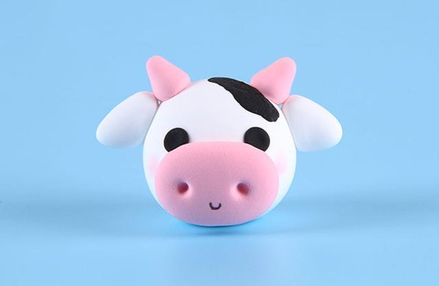 步骤5：把牛角和耳朵粘好，然后把黑色粘土粘在奶牛头上作为斑点。