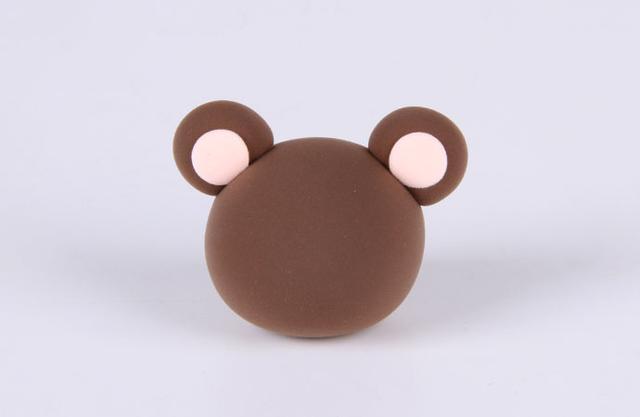 步骤5：然后用咖啡色和肤色粘土做出小耳朵，如上图所示，把做好的耳朵粘到头顶。