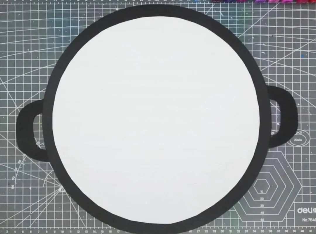 步骤2：白色纸剪刀剪去一圈，达到将它缩小一圈的目的。然后将剪好的白纸贴在黑纸上，将上一步剪好的黑色把手也粘在两侧。