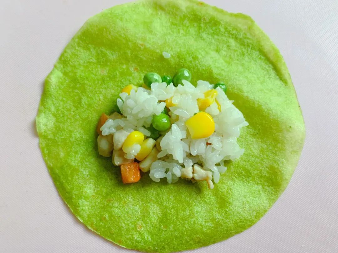 取一张菠菜饼皮，中间放入适量炒好的米饭。