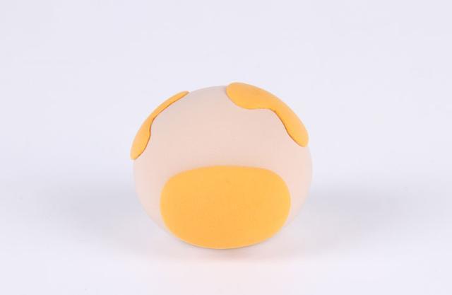 步骤2：用橙色黏土作出不两个不规则的形状贴在圆球上作为小牛身上的斑点，然后做一个椭圆形贴在嘴巴的位置，如上图所示。