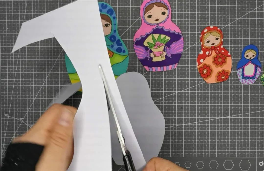 步骤5：多余的纸剪长条，再把长条剪成4小段，每小段对折，粘上双面胶。这个是下一步用来连接套娃和剪好的空白套娃的。