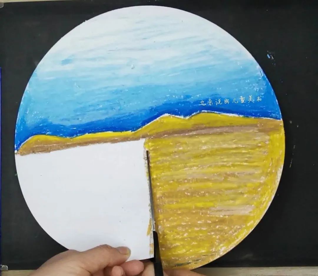 步骤7：剪刀把下半部分剪开，然后白色部分在下，画好沙漠的部分在上，用双面胶粘在一起。