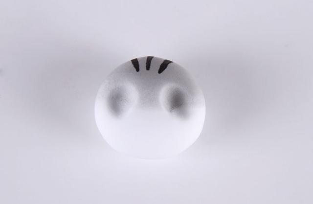 步骤2：揉好后的圆球是这个样子滴！头部的顶端是淡灰色，下面是白色的，这就是渐变色的小猫咪头部。做好之后我们用黑色笔在顶部画出三根黑色细条作为花纹，然后压出眼窝。