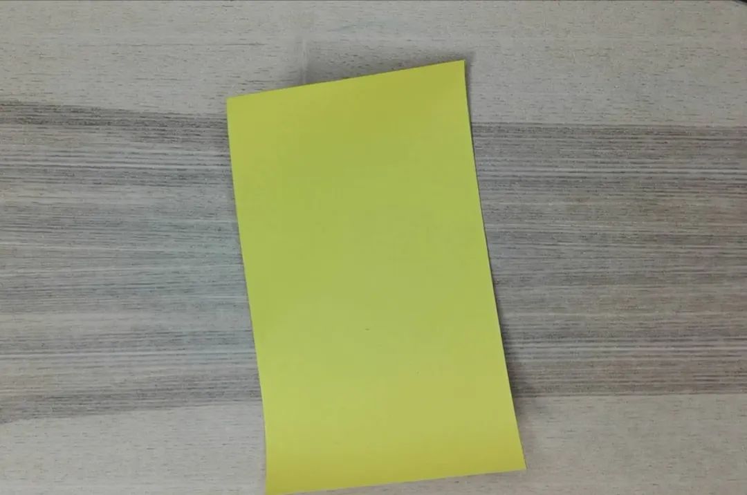 步骤3：取另一张黄色卡纸，剪下一半卷成一个直筒，双面胶粘住，这就是大公鸡的身体啦。