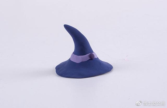 步骤5：用深蓝色粘土做出小魔女的帽子，如上图所示，并装饰上紫色的条纹。貌似女巫的帽子都是一样的，尖尖的，大家可以根据自己的喜好装饰上各种饰品。