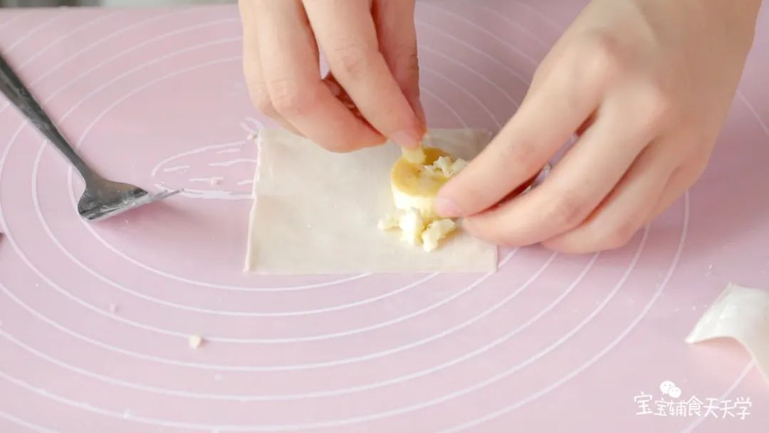 把香蕉和奶酪放到云吞皮里，对折包起来，稍微按压一下