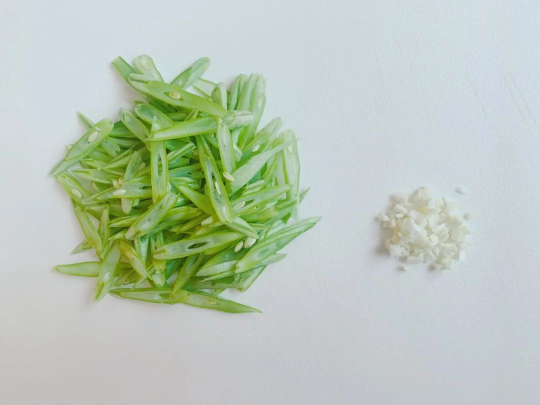 四季豆洗净去掉豆筋，斜刀切成小薄片。大蒜去皮切碎。