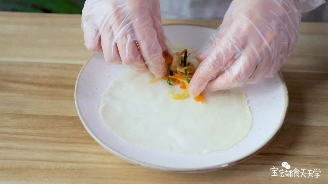 取出饺子皮撕开一张张成薄片春卷皮，三丝冷却后包入春卷皮中