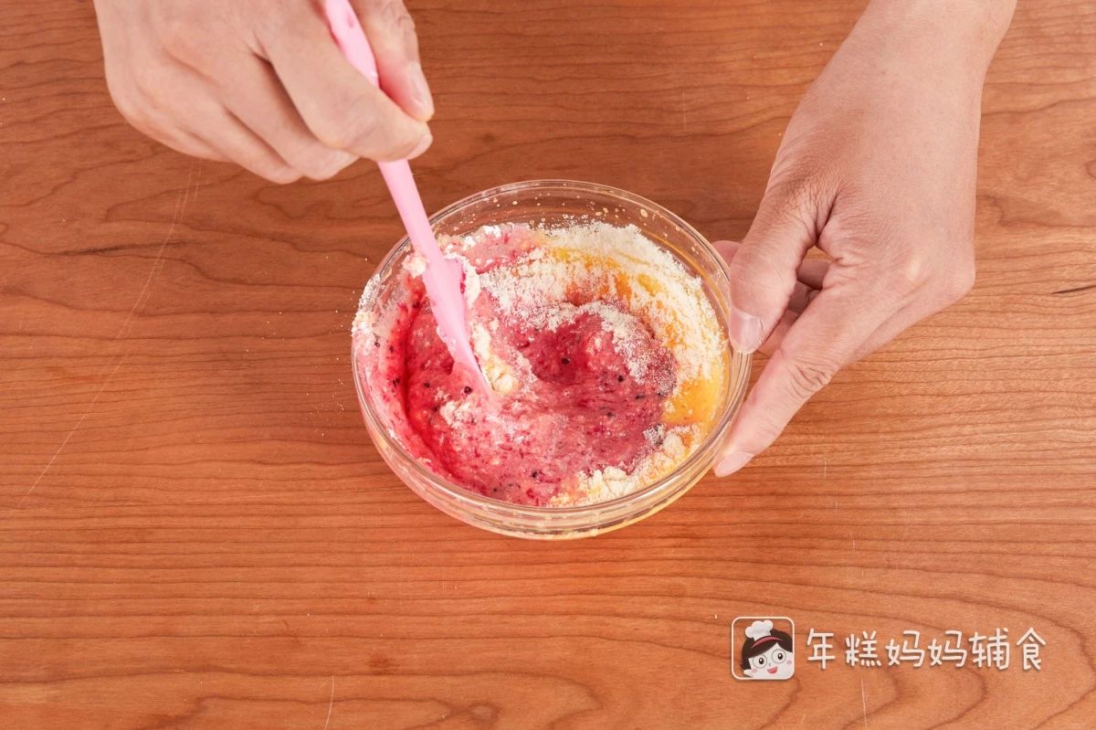 第5步：往打发好的蛋黄液中加入一勺火龙果泥、奶粉、糖粉，用刮刀翻拌均匀，搅拌至不滴落状态就可以了；